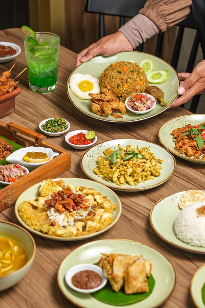 Vibrant Indonesian feast featuring nasi goreng, satay, and various traditional dishes on a wooden table.