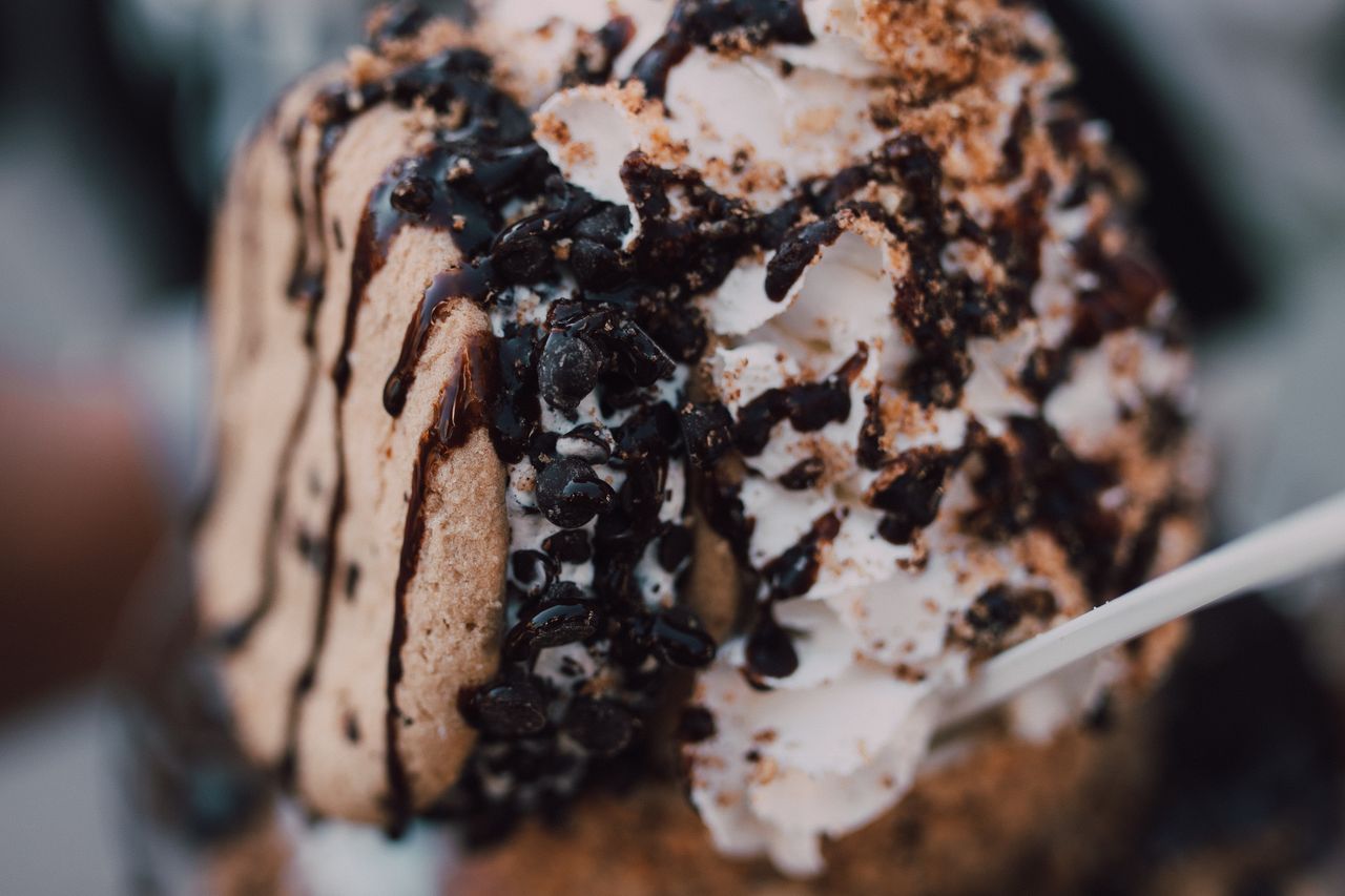 Close-up of a rich ice cream dessert topped with chocolate drizzle and cookie crumbles.